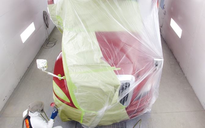 Technician painting a truck body in paint chamber