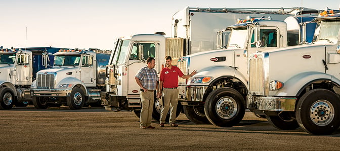 Rush Truck Centers salesman walking past used trucks with customer