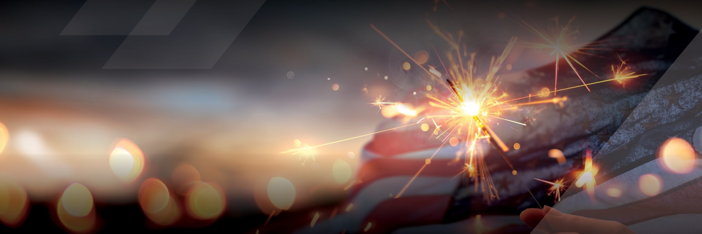 Person holding sparkler in front of American flag