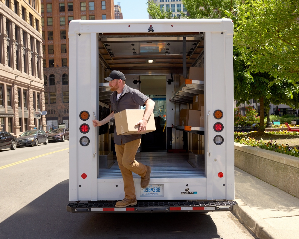 Delivery driver stepping out of the back of Blue Arc Class 4 walk-in van