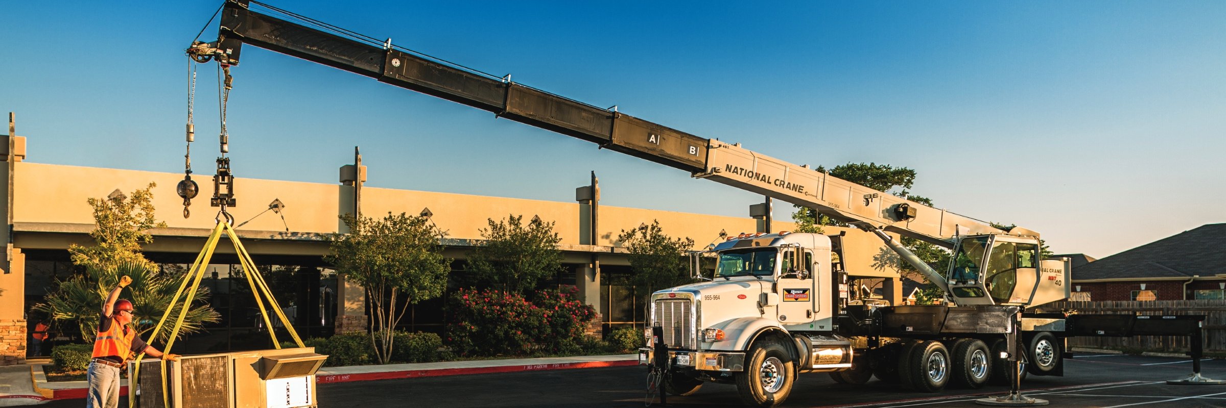 worker using a National Crane truck to lift an HVAC unit | Crane Trucks | Crane Truck Sales | Crane Trucks for Sale